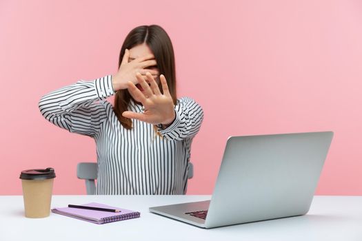 I dont want to look at this. Nervous woman office worker closing eyes with hand showing stop gesture, rejecting extra work, scared of harassment. Indoor studio shot isolated on pink background