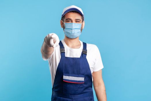 Hey you. Portrait of happy handyman in overalls, mask and gloves, pointing finger to camera. Profession of service industry, builder and house maintenance. Expert repairman in workwear making choice