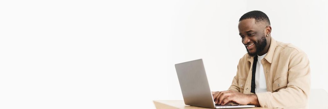 Web banner. Smiling professional black business man using laptop computer working from home office. Happy afro american freelancer man working at home.