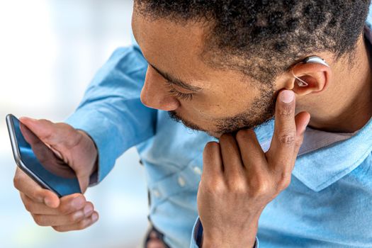 Young man adjusts the intensity of the volume of the auditory headset with the smartphone