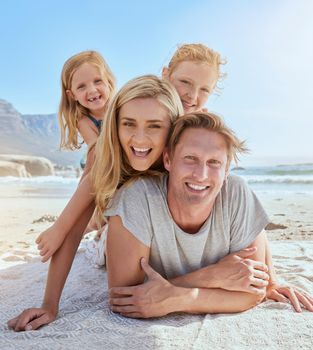Portrait of a carefree family relaxing and bonding on the beach. Two cheerful little girls having fun with their parents on holiday. Mom and two daughters lying on top of dad enjoying vacation.