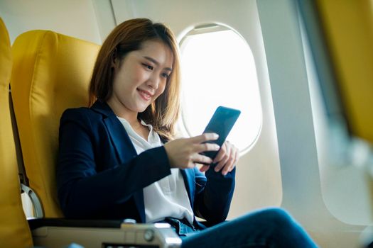 Young businesswoman In a plane using using on phone computer during In a plane flight, travel concept.
