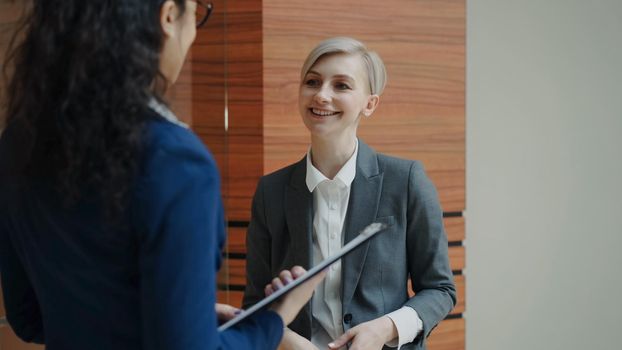 Two businesswomen colleagues talking in modern office indoors