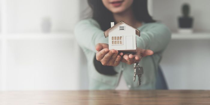 Close up Business woman or Real Estate agent giving house key after signing agreement for buying house. Bank manager and real estate concept