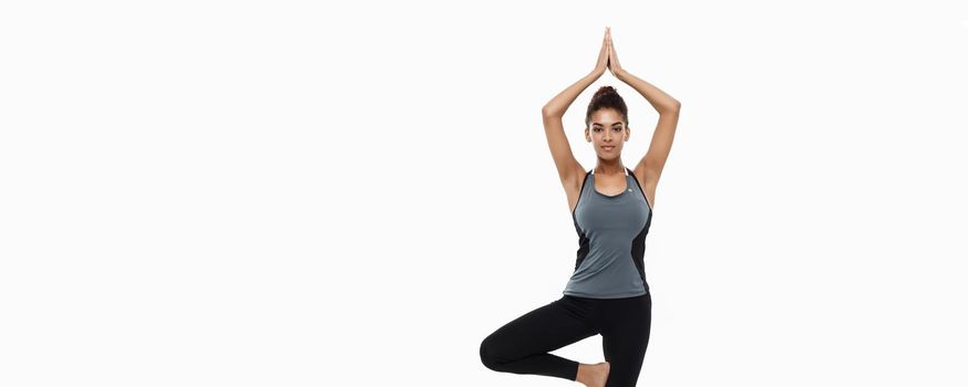 Healthy and Fitness concept - Beautiful American African lady in fitness clothing doing yoga and meditation. Isolated on white background