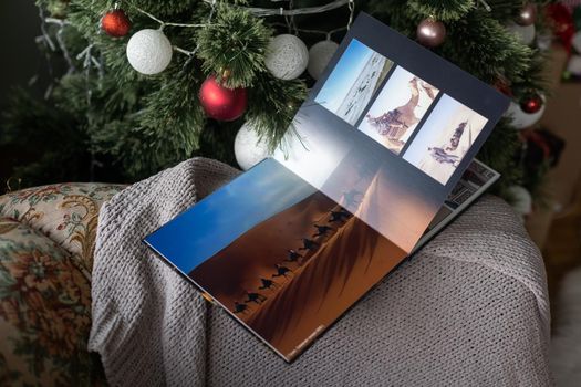 Photo book family photo album under the Christmas tree surrounded by Christmas gifts.