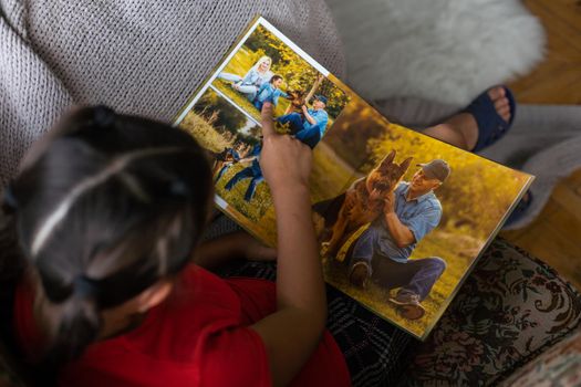 a little girl looking at a photo album in the living room.