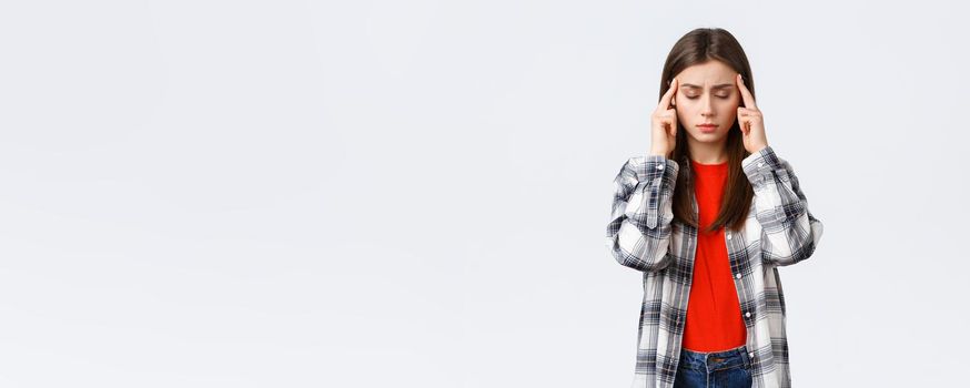 Lifestyle, different emotions, leisure activities concept. Distressed and exhausted young female student trying focus, feel headache or dizzy, close eyes and rub temples, white background.