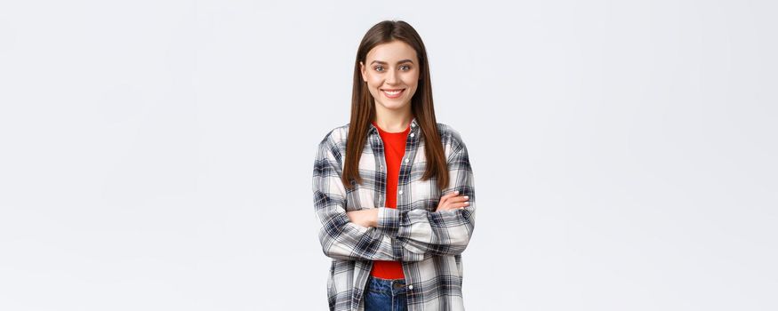 Lifestyle, different emotions, leisure activities concept. Cheerful young caucasian girl, female student in checked casual shirt, cross arms chest and demiling pleased, standing white background.