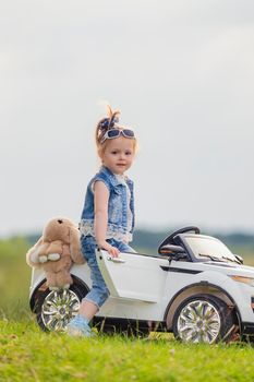 small child stands near his car on the lawn