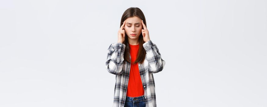 Lifestyle, different emotions, leisure activities concept. Distressed and exhausted young female student trying focus, feel headache or dizzy, close eyes and rub temples, white background.