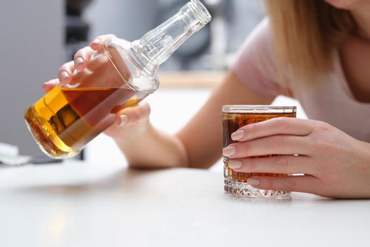 Woman drinks alcohol cognac or whiskey alone. Alcohol abuse or drinking concept