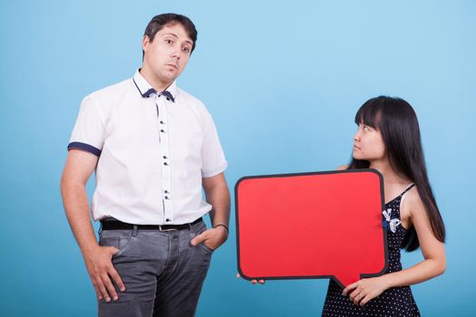 Asian girlfriend holding empty bubble thoughts and looking at her confused caucasian boyfriend. Interracial couple.