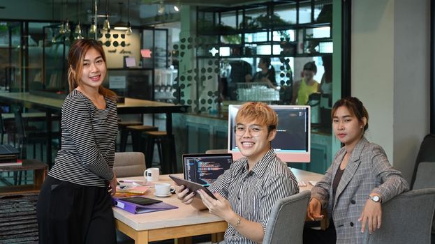 Team of computer programming specialist sitting working together in software company office.