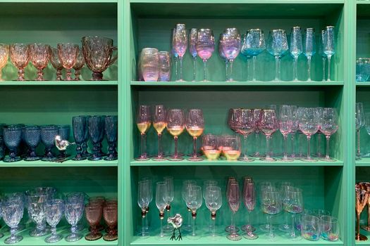collection of beautiful colourful glasses on wooden shelves