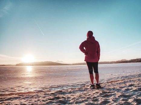 Image from side of athlete woman on beach run in winter morning.