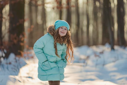 little girl in a winter forest and turquoise-colored clothes