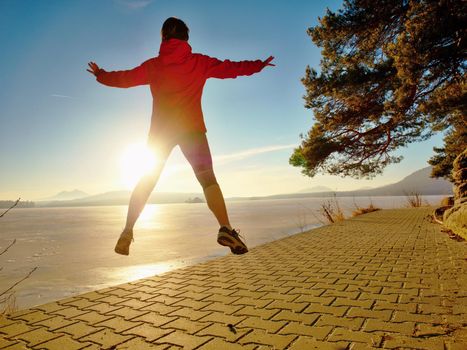 Sports girl runs through the morning park by the lake