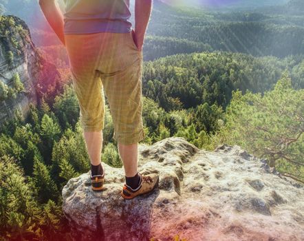 Hiker man stays on the mountain hill during hiking. Hker staying on Rock and looking down to valley