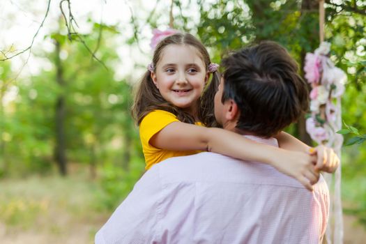 Smiling little girl hugging her father outside