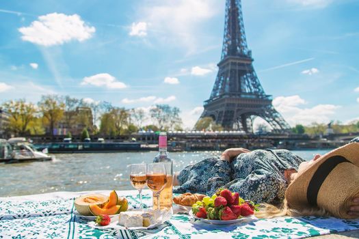 A woman near the Eiffel Tower drinks wine. Selective focus. People.