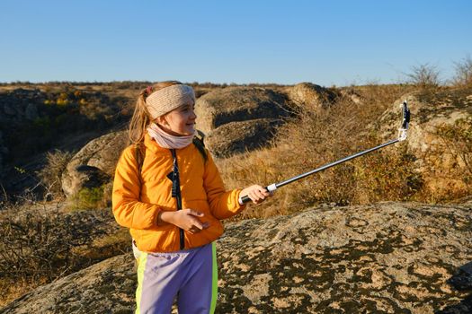 Shot of a kid girl talking on camera in hills, make video blog use device make video hold hand social network blog. child vlogger filming video diary outdoors. kid creating social media content.