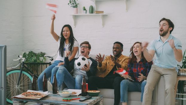 Multi-ethnic group of friends sports fans with Austrian flags watching football championship on TV together at home indoors and cheering up favourite team