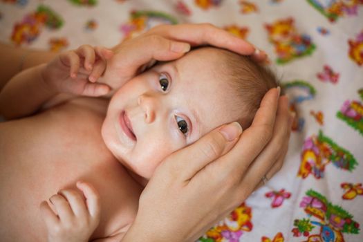 Mother holding head of her newborn daugther in hands. The baby on hands at mum. Loving mother hand holding cute smiling newborn baby child