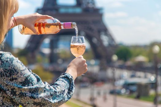 A woman pours wine near the Eiffel Tower. Selective focus. People.