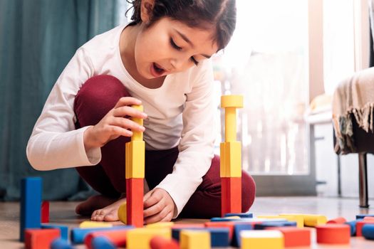 little girl playing at home with building blocks, concept of indoor leisure for children