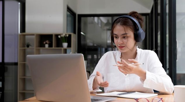 Smiling girl in headphones sit at desk look at laptop screen study online, happy smart young woman in earphones take web course or training on computer, distant education concept.