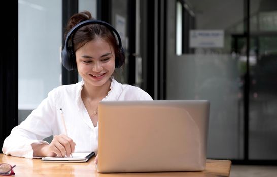 Young woman having online training, using laptop and wireless headset.