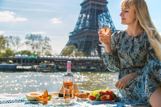 A woman near the Eiffel Tower drinks wine. Selective focus. People.