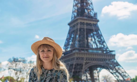 A woman in a hat looks at the Eiffel Tower. Selective focus. People.