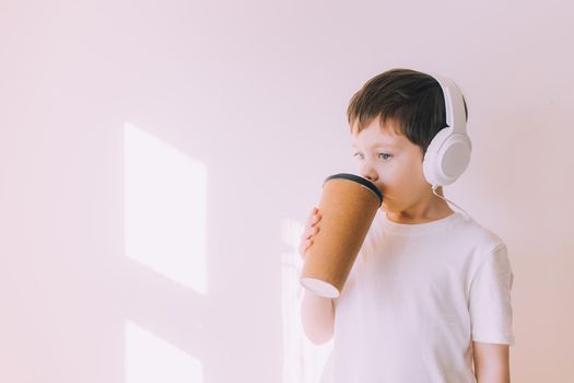 The boy listens to music with lifestyle headphones . Modern technologies. Kids and gadgets. Music for children. Modern children. Smartphones in children. Copy space. White background.