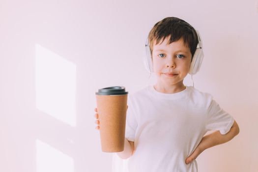 The boy listens to music with lifestyle headphones . Modern technologies. Kids and gadgets. Music for children. Modern children. Smartphones in children. Copy space. White background.