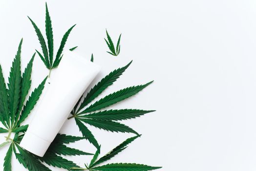 Tube with hemp oil moisturizer on white background with copy space and mockup. Cannabis in the production of cosmetics for skin care.