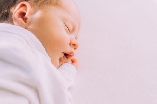 The lifestyle of a sleeping newborn baby on a white background. A sweet childhood dream. An article about newborns.