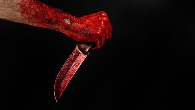 Man holding knife with bloody hand on black background