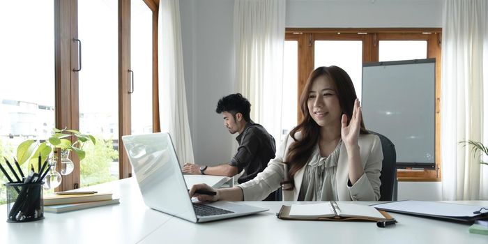 Asian female talking about sale report in video conference. Asian team using laptop and tablet online meeting in video call.Working from home remotely..