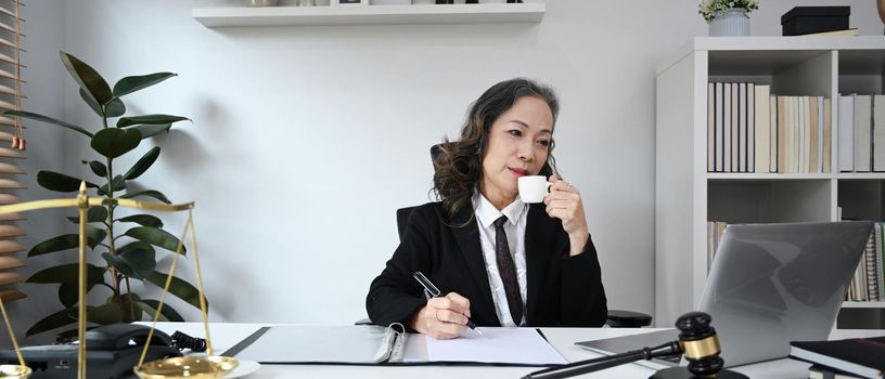 Positive middle aged female lawyer working with laptop at home office. Lawyer, justice and law ,attorney, concept.