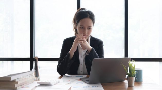Image of an Asian woman who is tired and overthinking from working with a tablet at the office..
