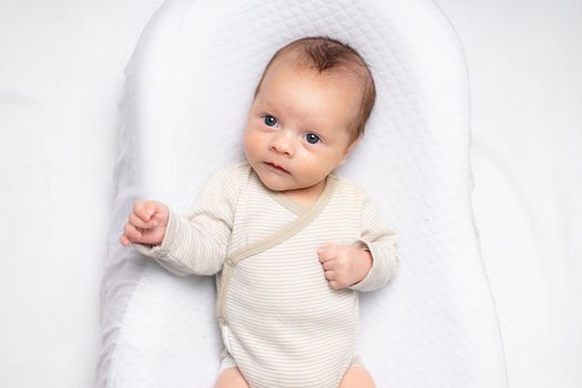 The baby is lying in a cocoon of copy space . The baby is 0-3 months old. A contented infant. An article about choosing a cocoon for newborns. An article about the benefits of cocoon. An article about colic .