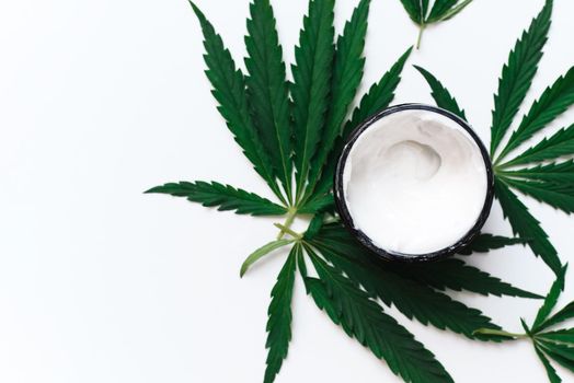 Moisturizing cream with hemp oil on a white background with copy space. The use of cannabis in the production of cosmetics for skin care.