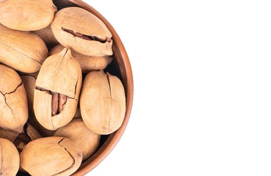 Pecan nuts in a ceramic bowl close-up on a white background, top view