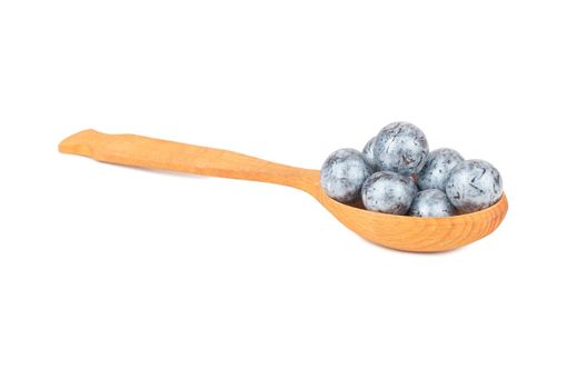 Round chocolate candies in a spoon close-up on a white background