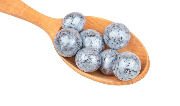 Round chocolate candies in a spoon close-up on a white background