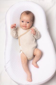 The baby is lying in a cocoon of copy space . The baby is 0-3 months old. A contented infant. An article about choosing a cocoon for newborns. An article about the benefits of cocoon. An article about colic .