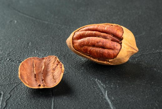 Cracked in-shell pecan close-up on dark concrete background