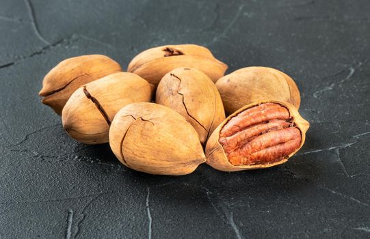 Small pile of inshell pecans close up on a dark background